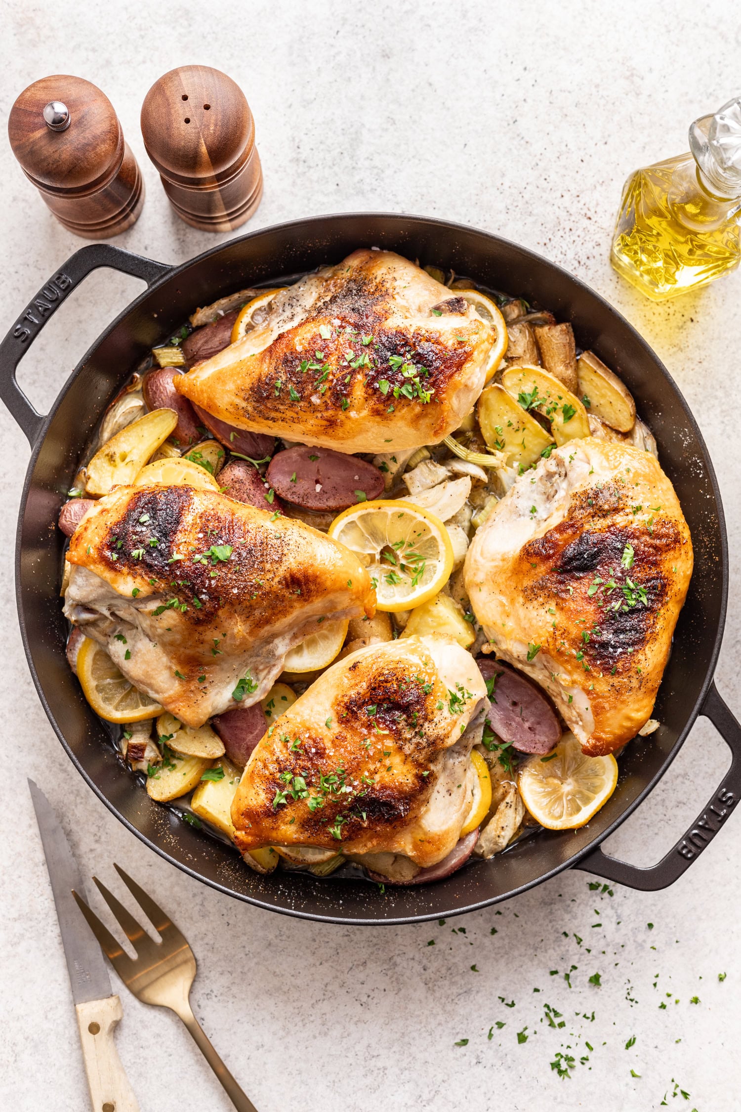 cast iron skillet with cooked chicken, potatoes and lemon