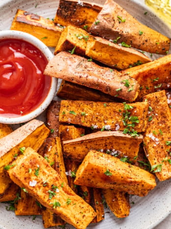 sweet potato wedges with a side of ketchup and chopped parsley sprinkled on top