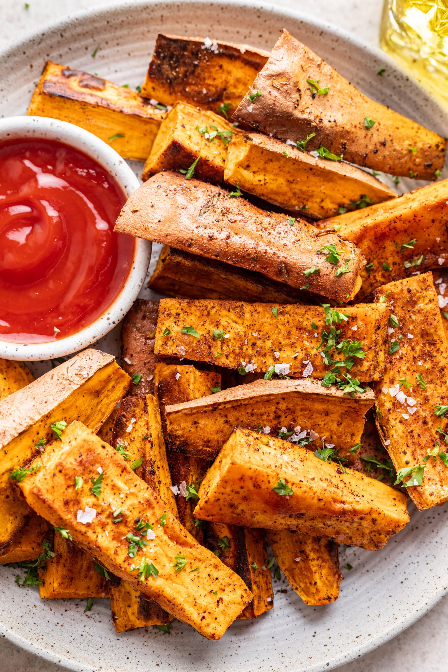 sweet potato wedges with a side of ketchup and chopped parsley sprinkled on top