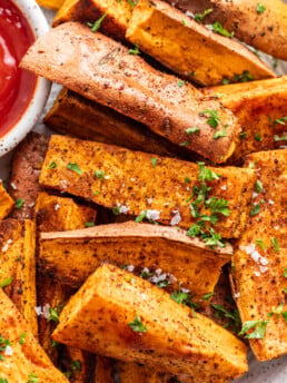sweet potato wedges with a side of ketchup and chopped parsley sprinkled on top