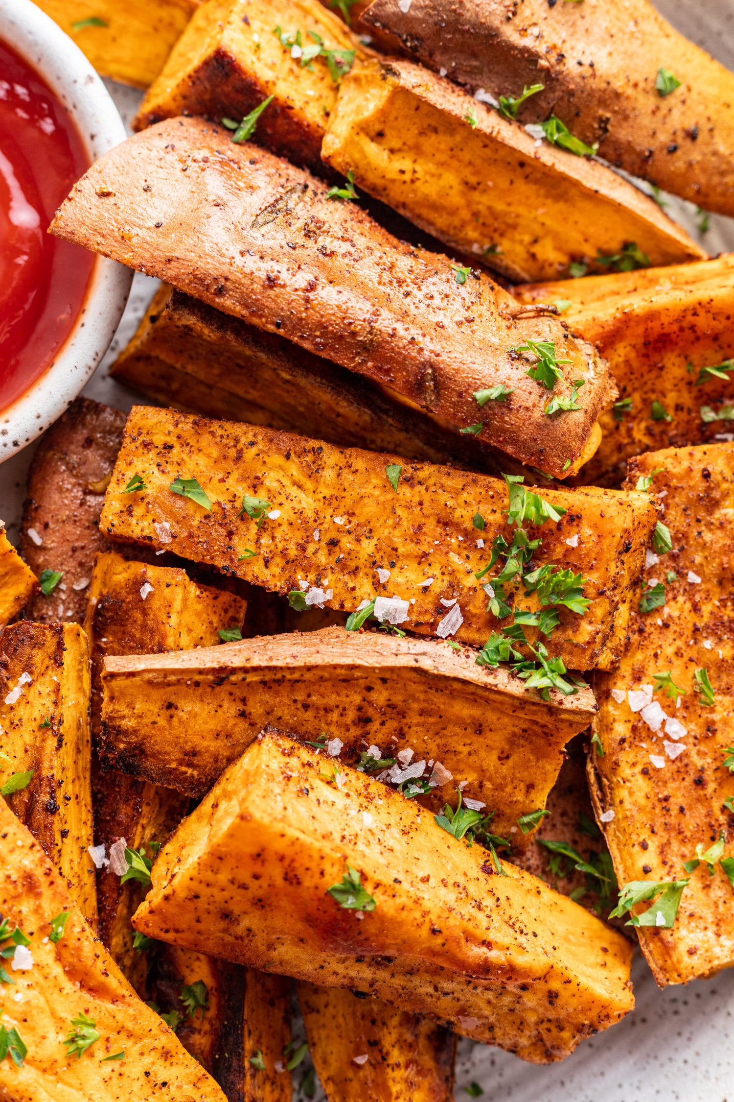sweet potato wedges with a side of ketchup and chopped parsley sprinkled on top