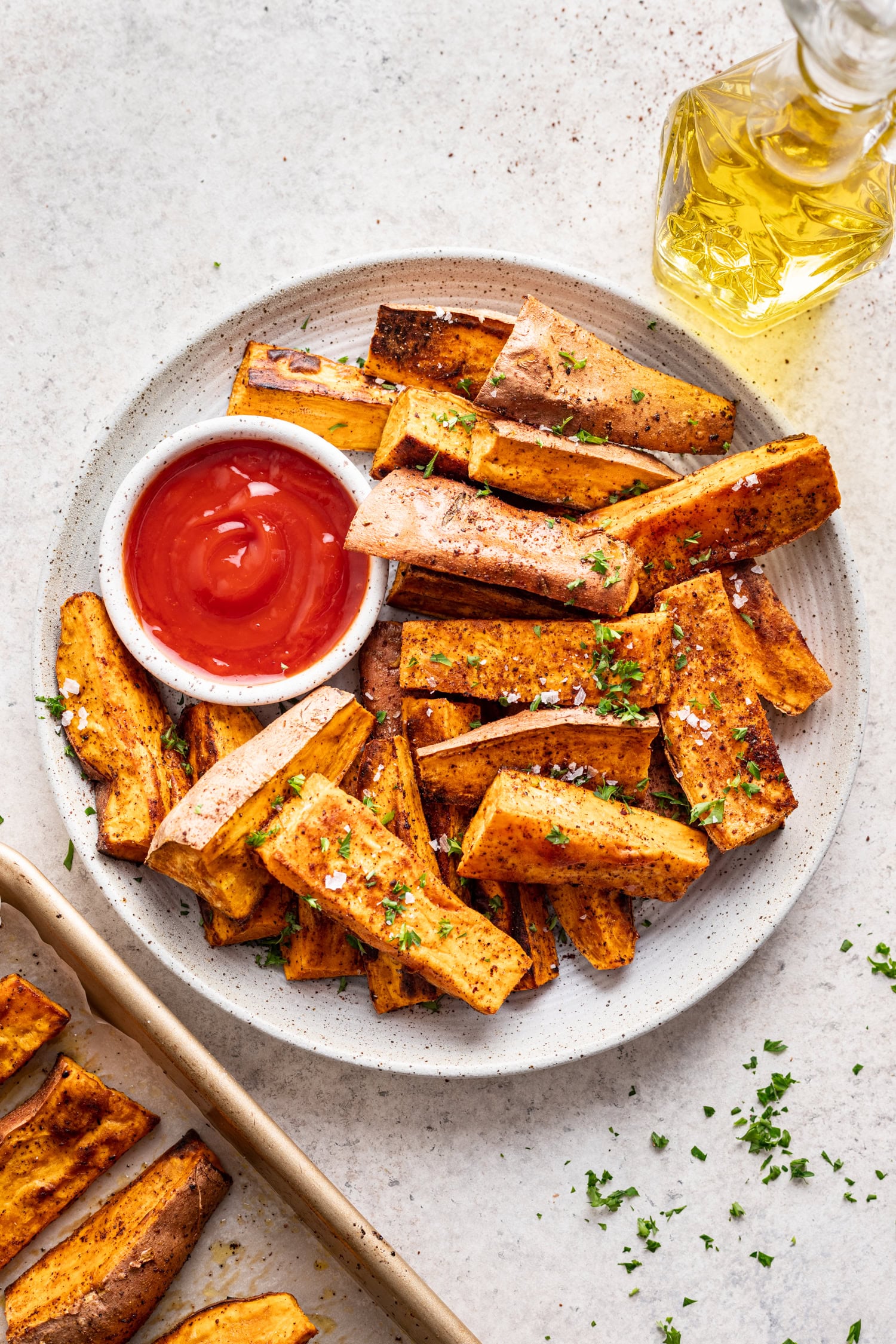 roasted sweet potatoes on a while plate with a side of ketchup
