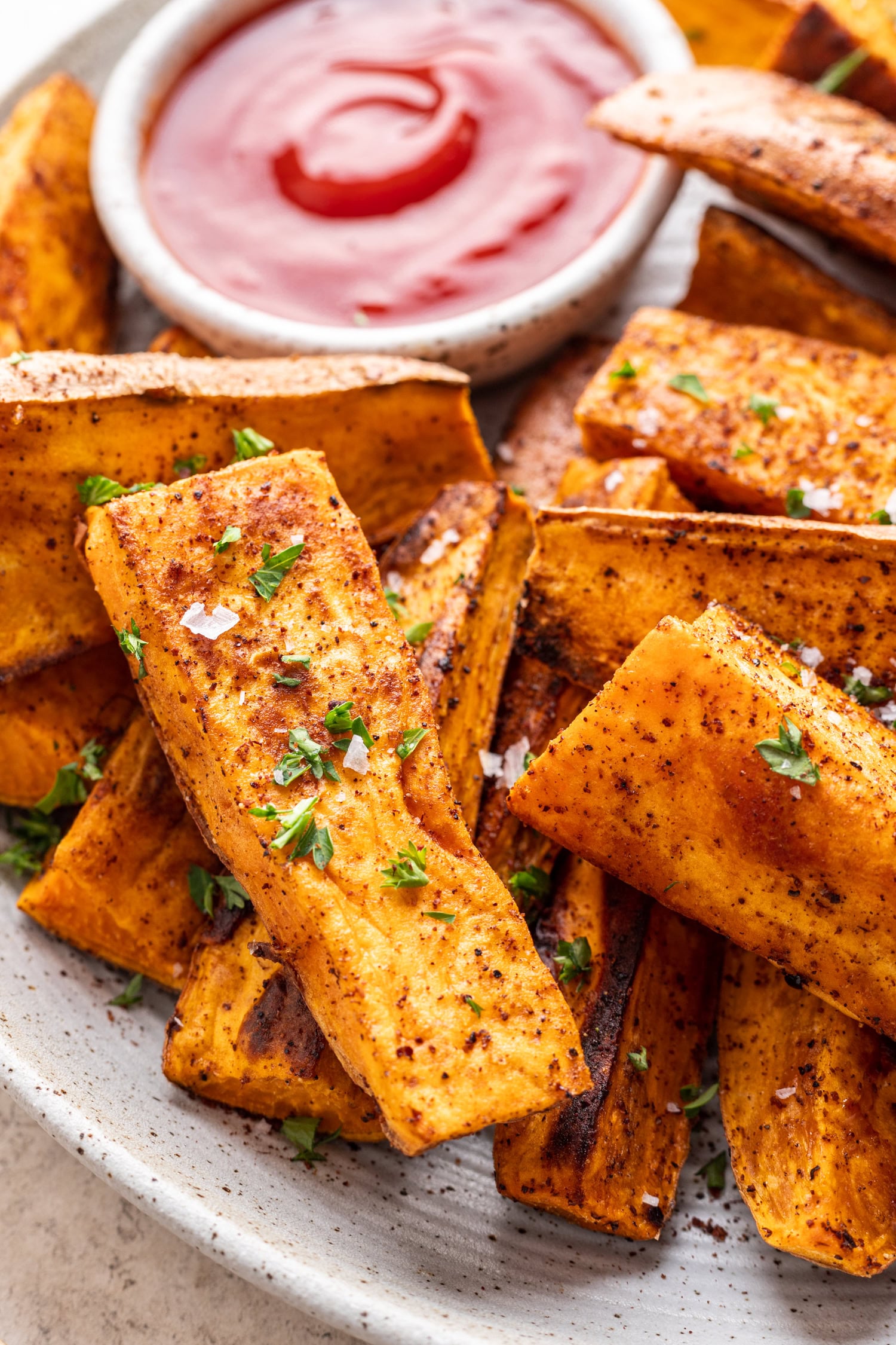 roast sumac sweet potato wedges with sprinkled parsley and a side of ketchup