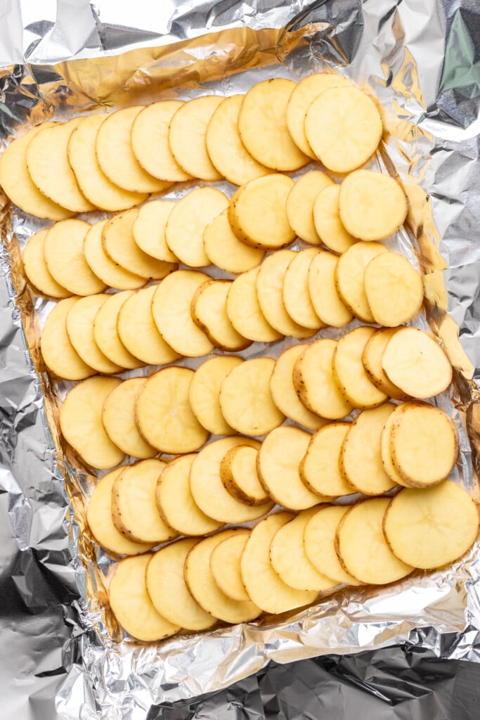 Sliced yukon gold potatoes on a foil lined sheet pan