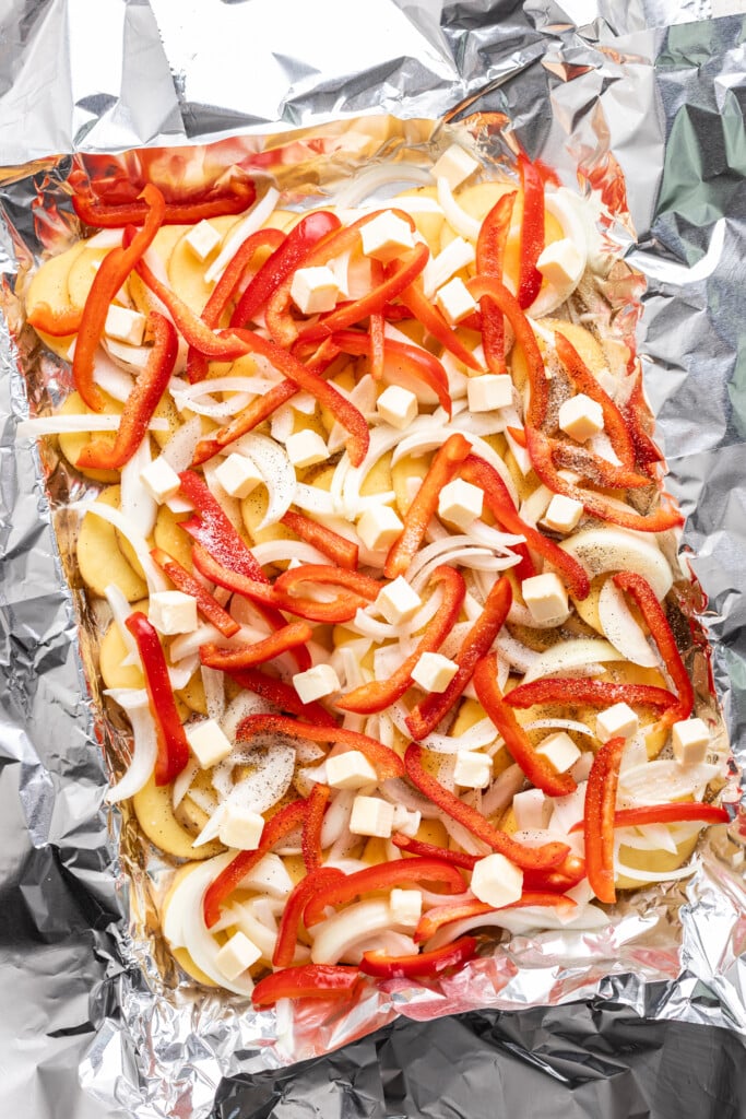 potatoes, onion, bell peppers and butter on a foil lined sheet pan