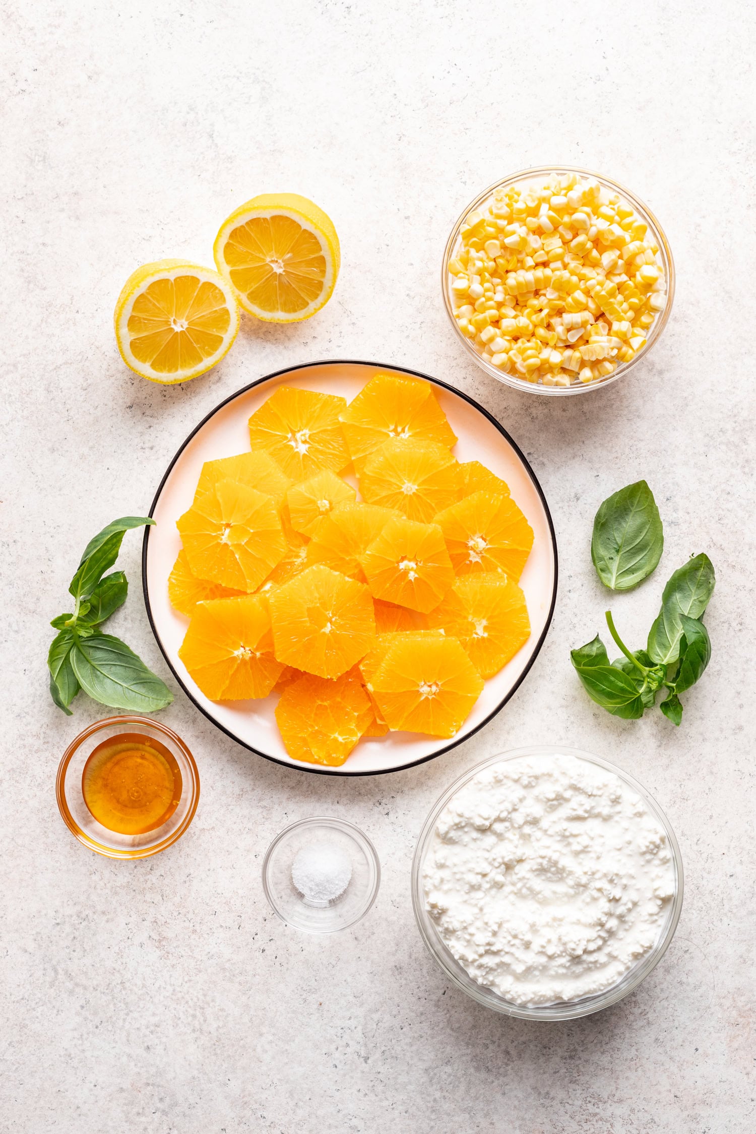 ingredients in bowls like sliced oranges, raw corn, cottage cheese and lemons