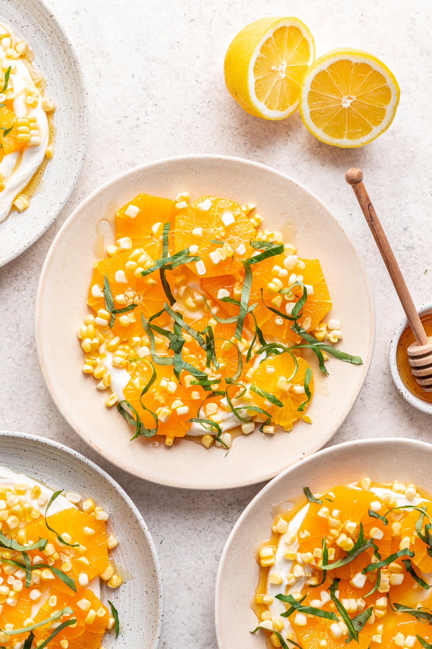 plate with sliced oranges topped with raw corn and basil