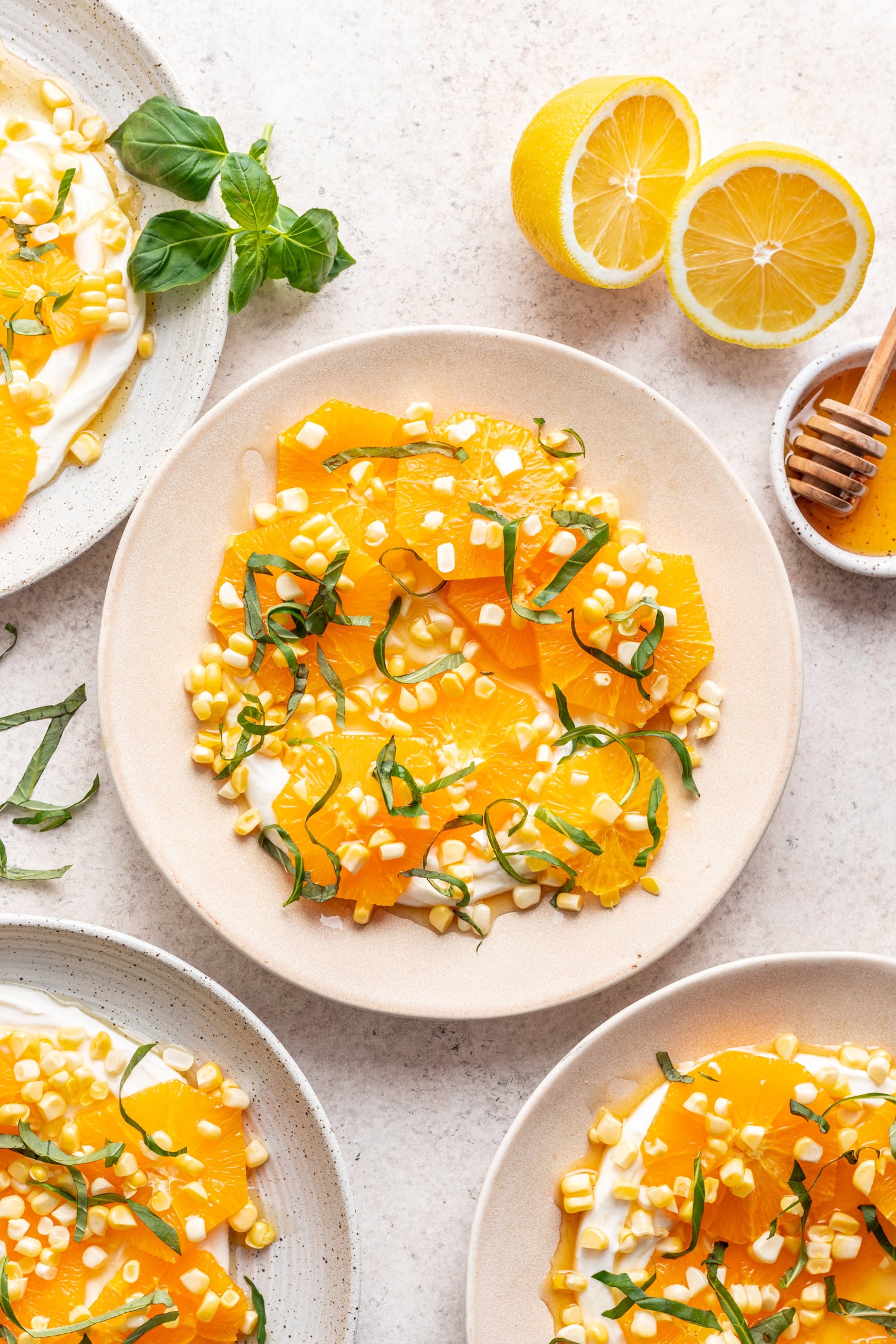 plate with sliced oranges topped with raw corn and basil
