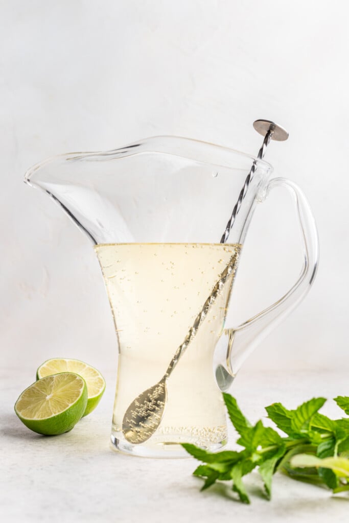 cocktail in a large glass pitcher with a long stirring spoon