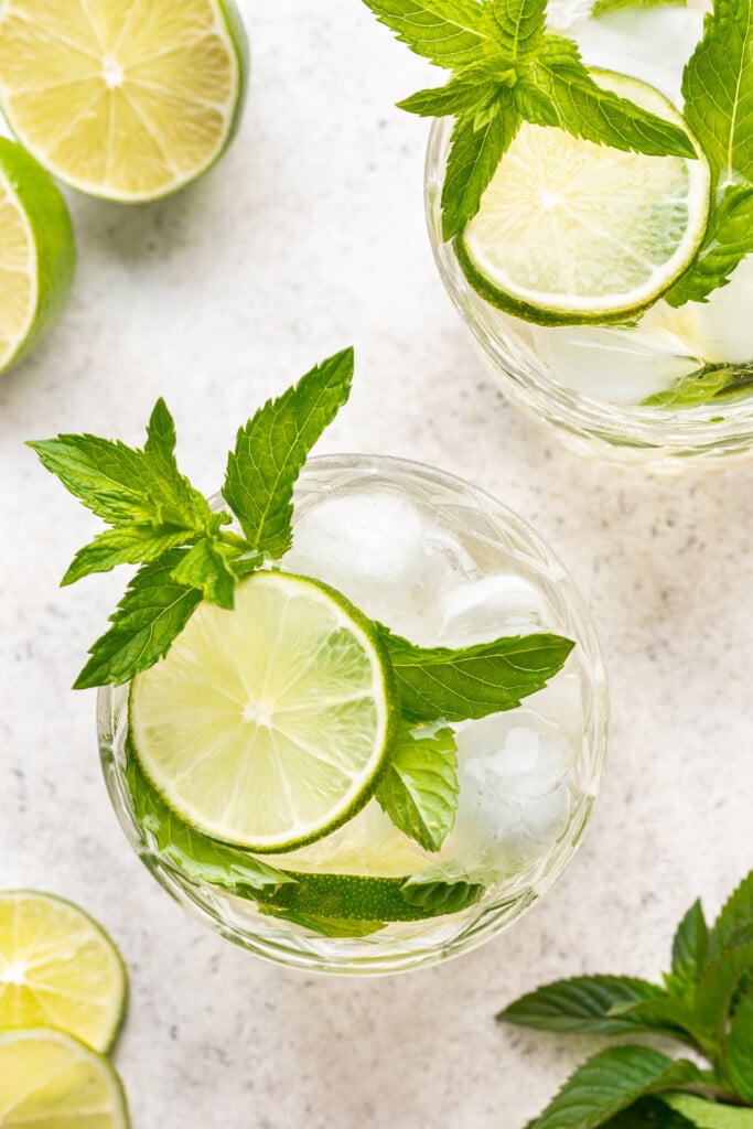 two glasses with a cocktail, fresh lime and mint