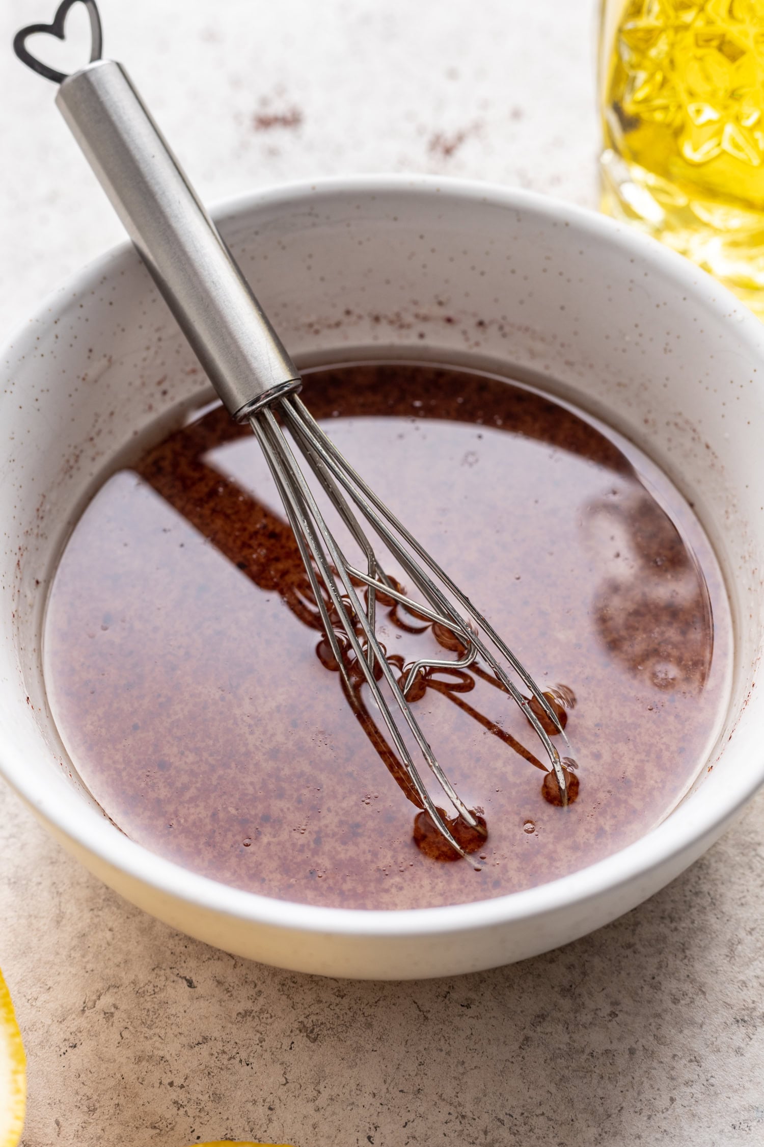 lemon sumac dressing in a white bowl with a whisk