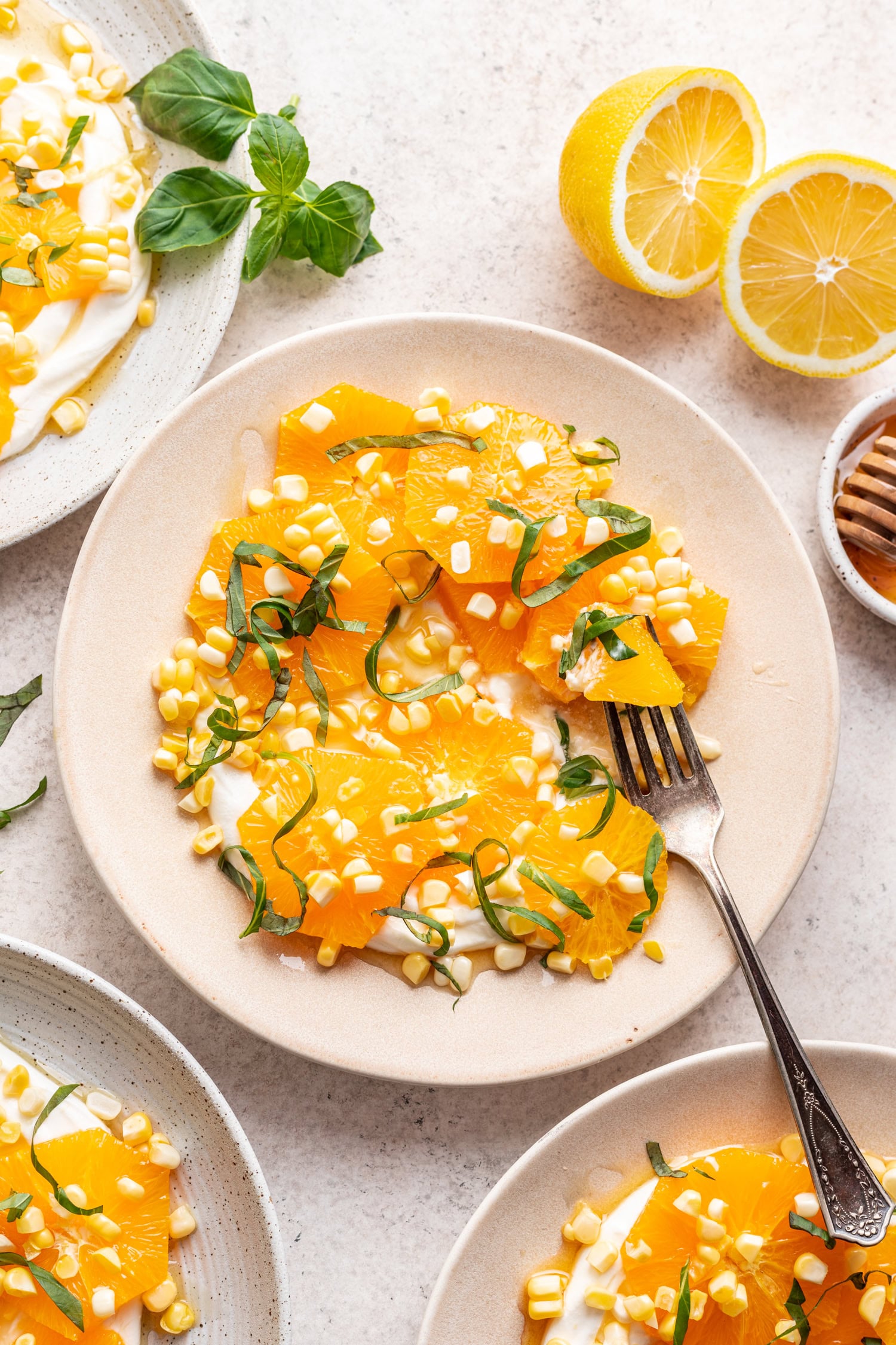 oranges on a plate with raw corn and fork
