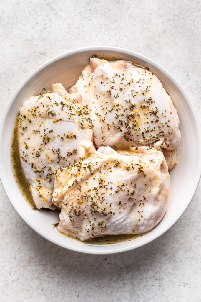 white bowl with 3 raw chicken thighs