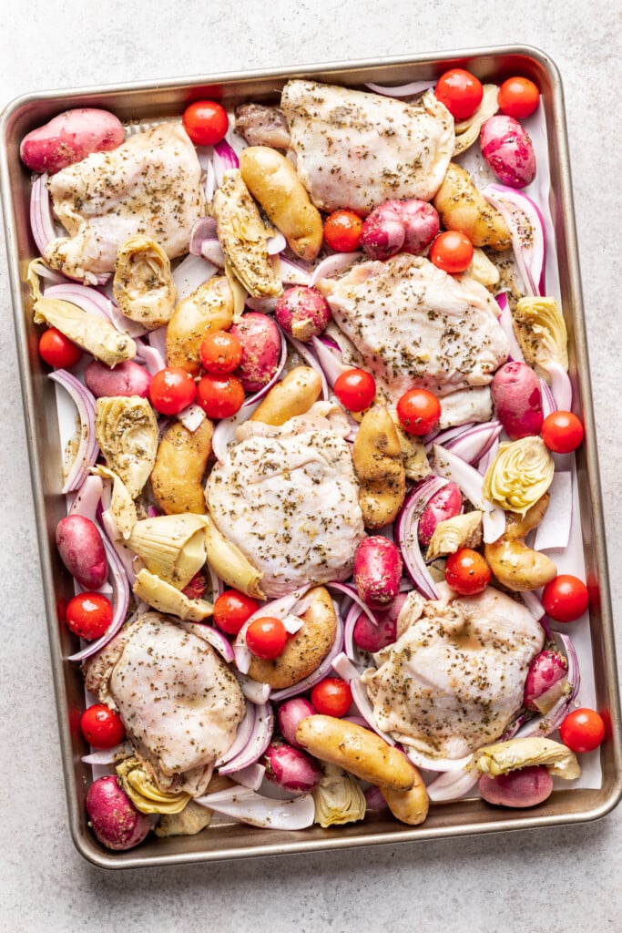 sheet pan with chicken thighs, tomato, potatoes and onion