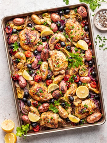 Chicken thighs on a sheet pan with roasted potatoes, olives and tomatoes