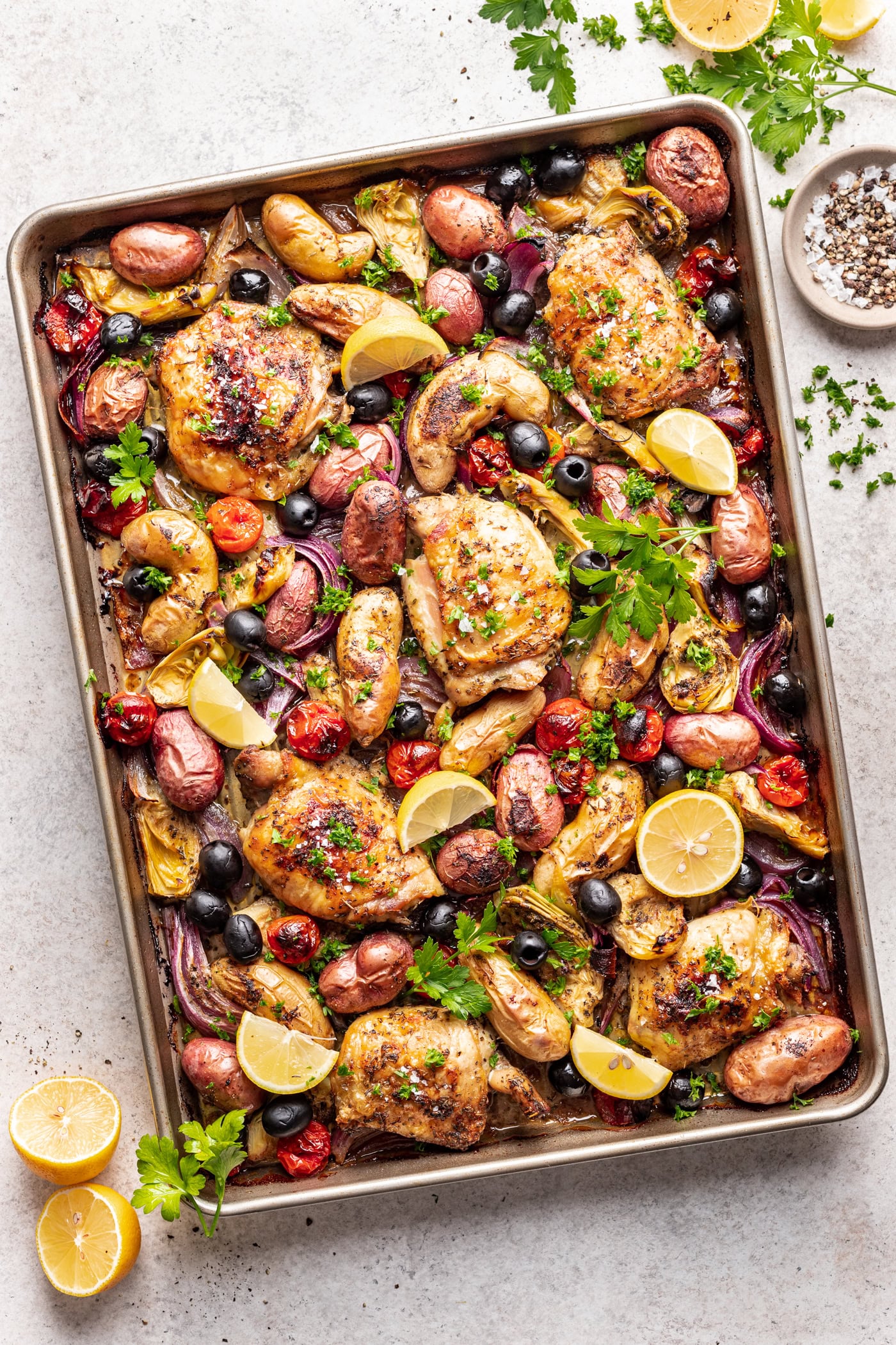 Chicken thighs on a sheet pan with roasted potatoes, olives and tomatoes