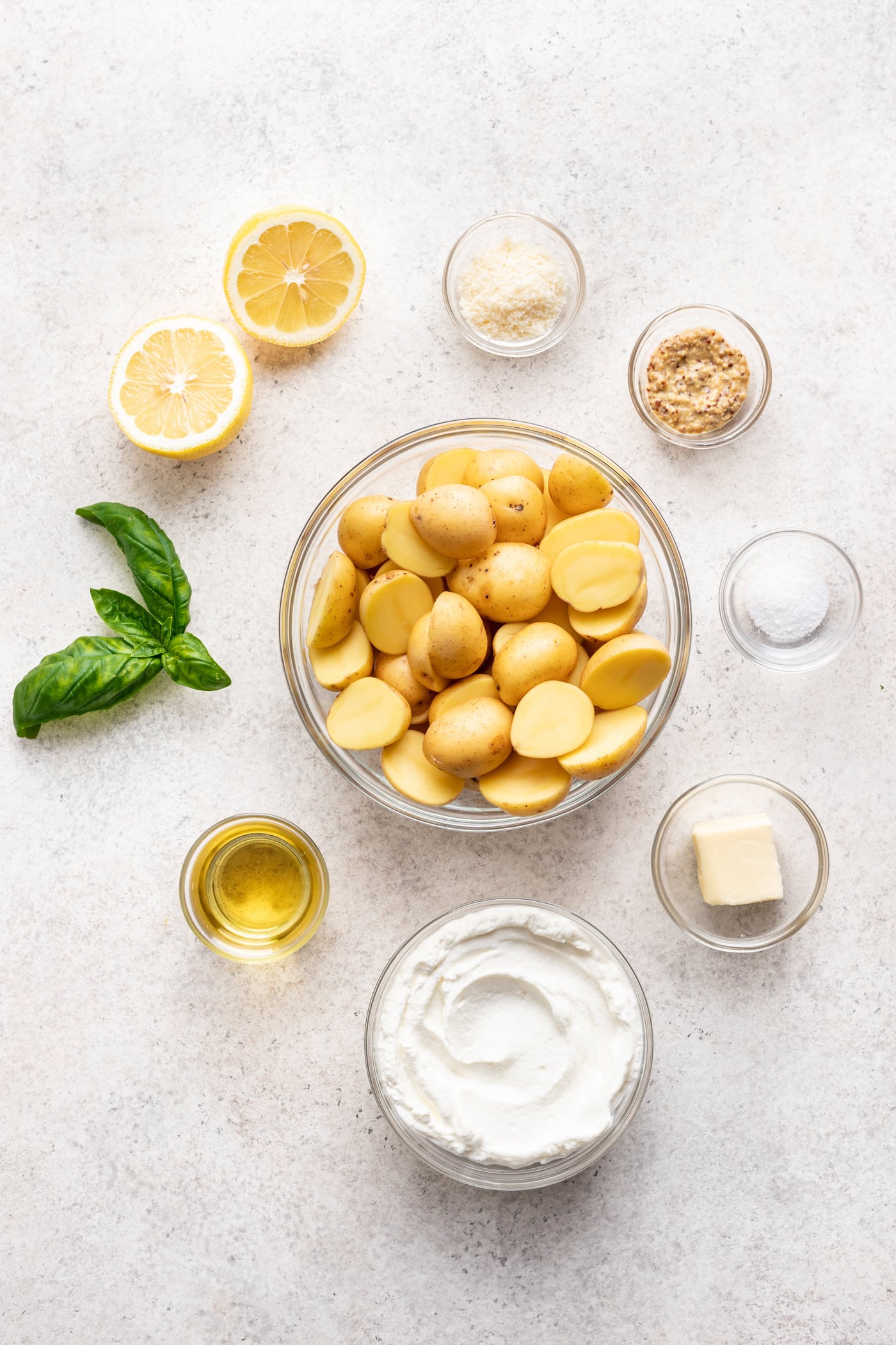 glass bowls with ingredients like potatoes, lemon, oil, yogurt.