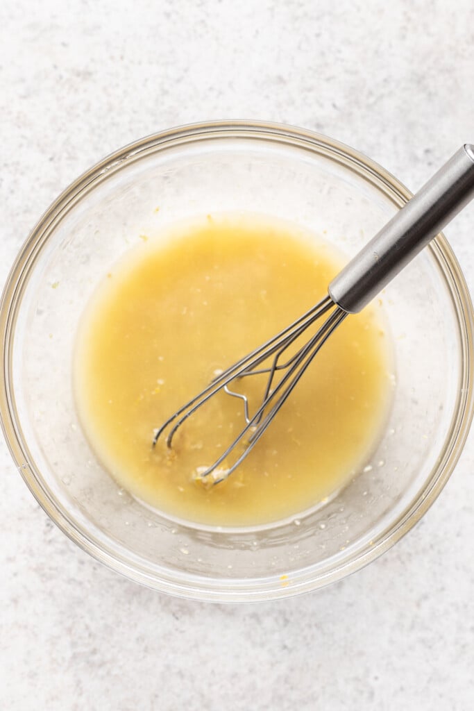 a bowl of dressing with a whisk
