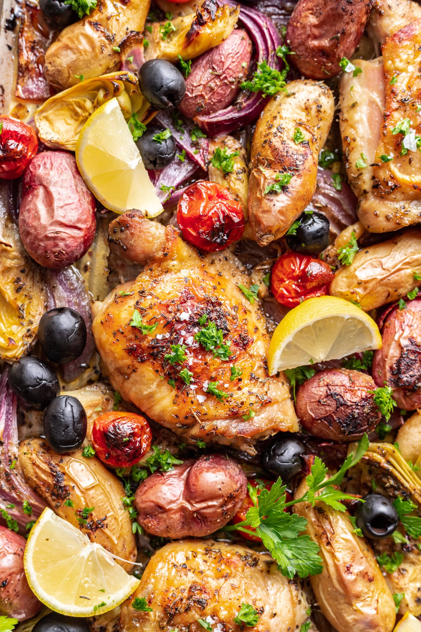 roasted chicken thigh with potatoes, olives and tomatoes with lemon slices