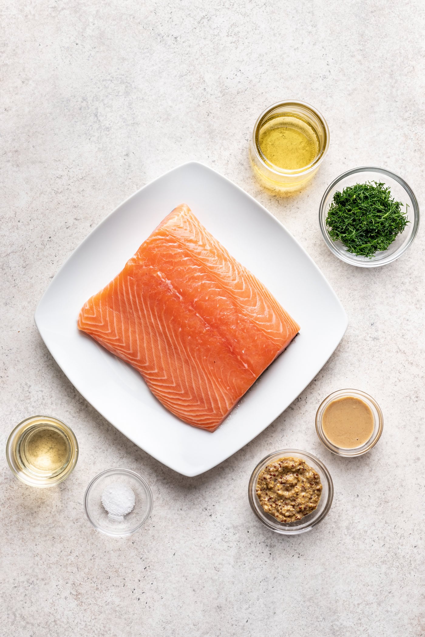 salmon filet on a white plate with small bowls surrounding