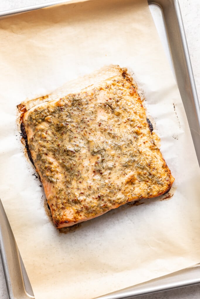 cooked salmon on a sheet pan with dill sauce