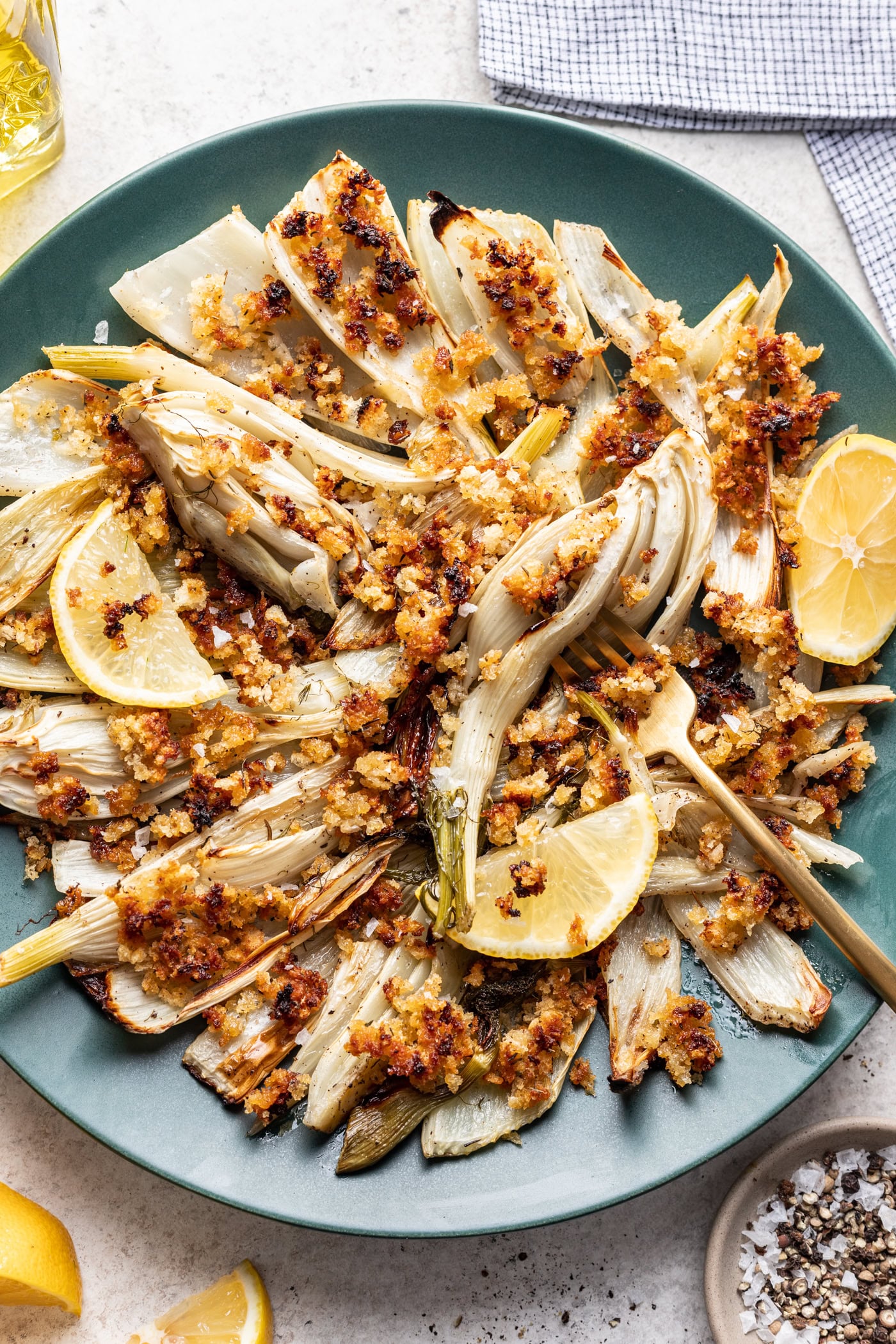 roast fennel on a blue platter with breadcrumbs and fork