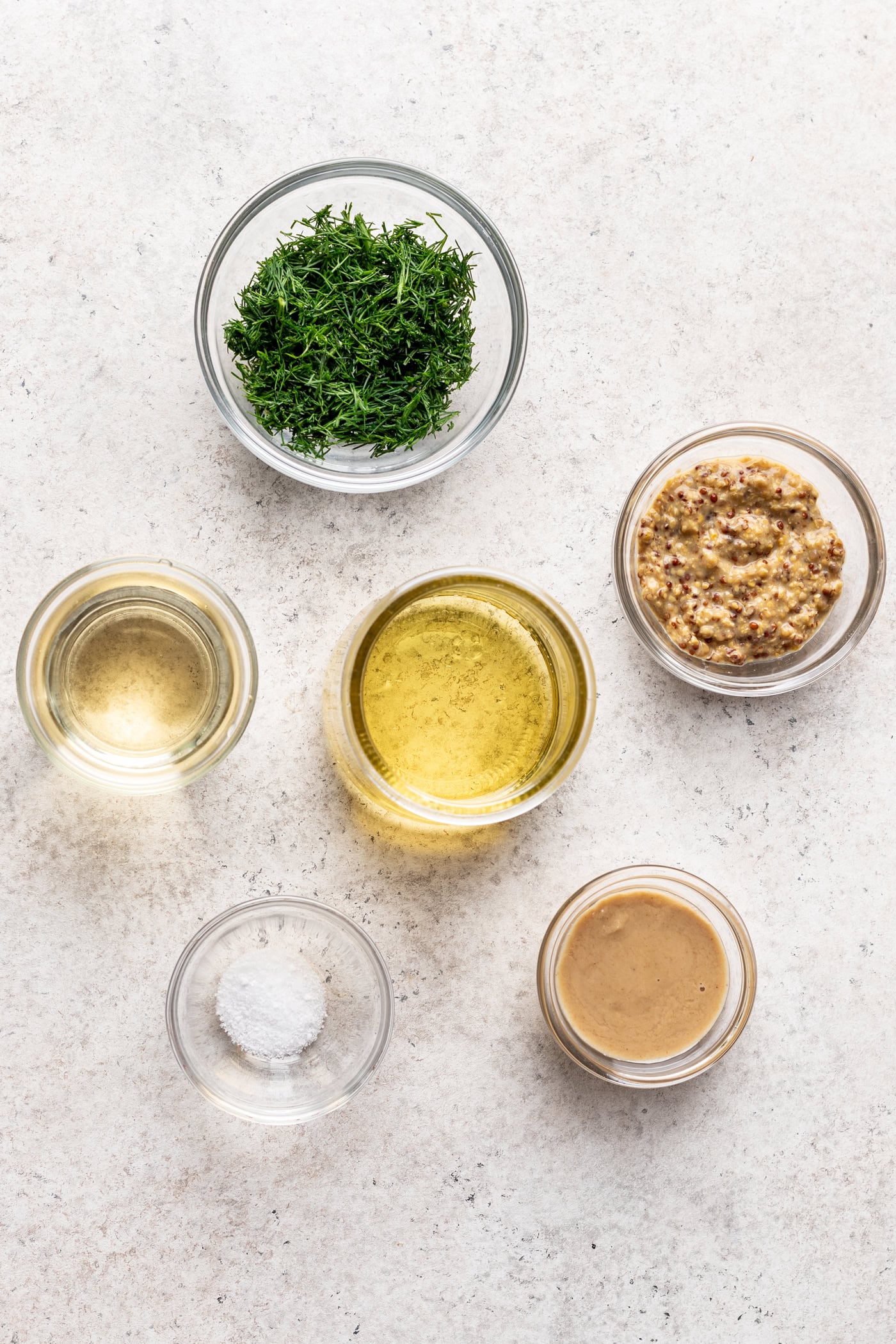 bowls of ingredients like oil, mustard and fresh herbs