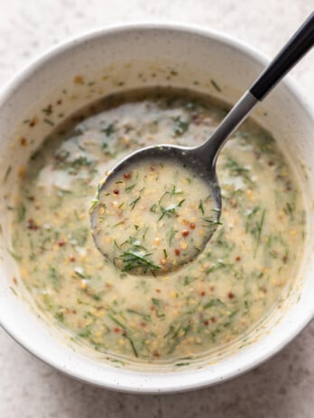 mustard dill sauce in a white bowl with a spoon