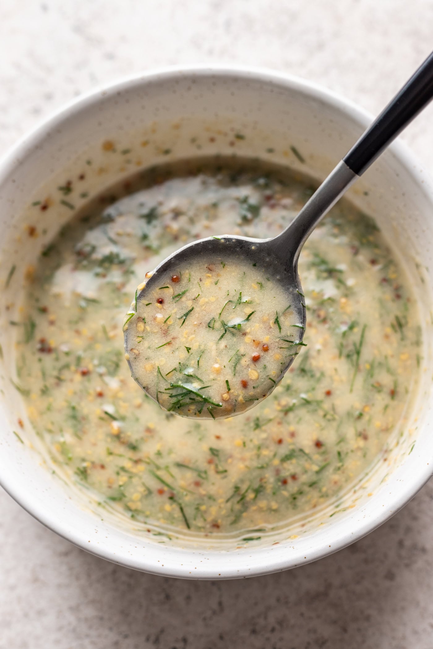 mustard dill sauce in a white bowl with a spoon