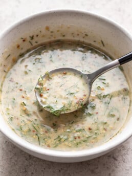 mustard dill sauce in a white bowl with a spoon