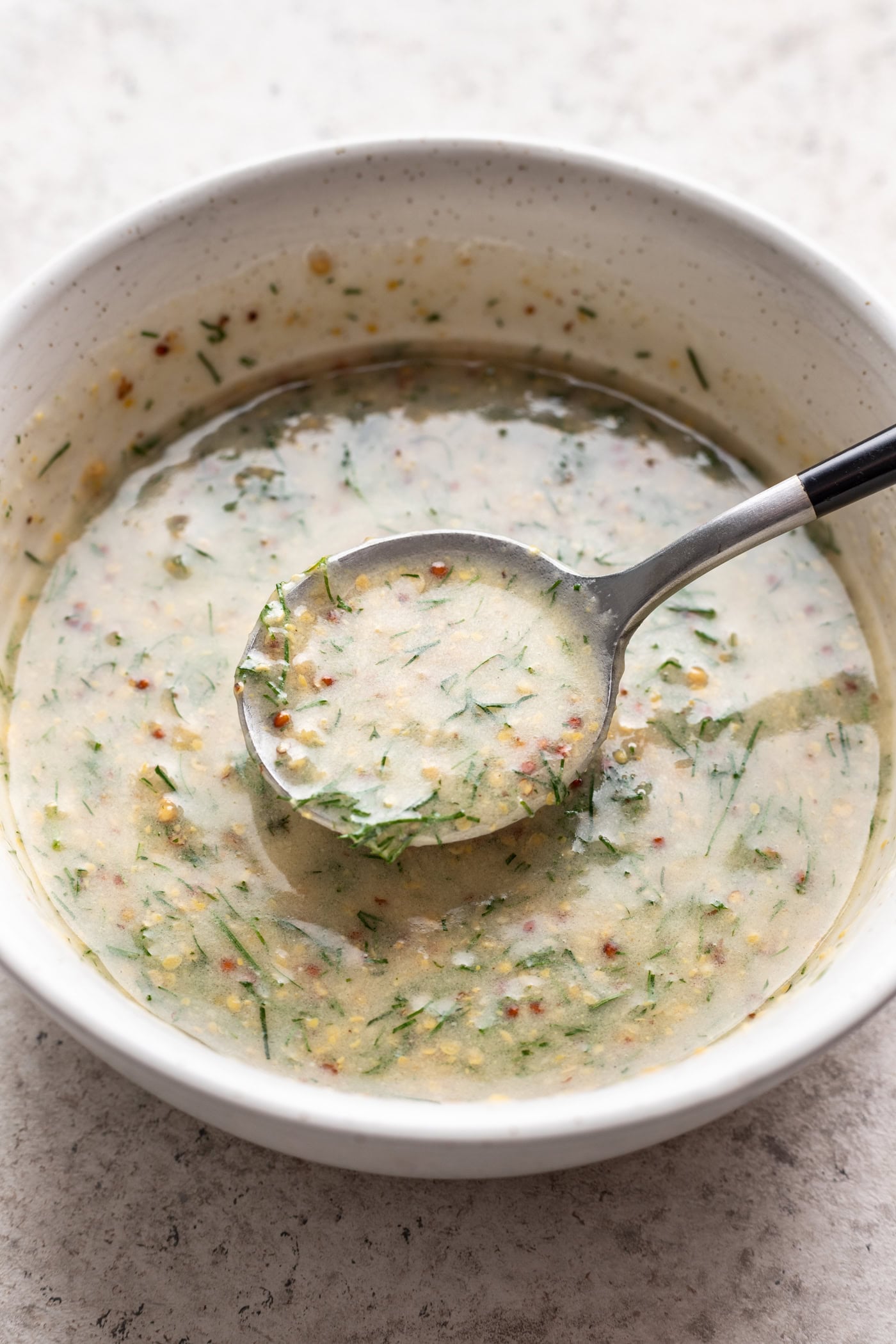 mustard dill sauce in a white bowl with a spoon