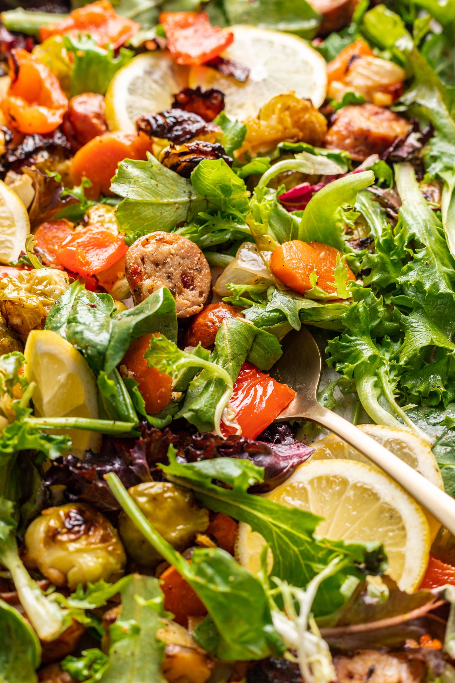 sheet pan sausage and veggies with a serving spoon