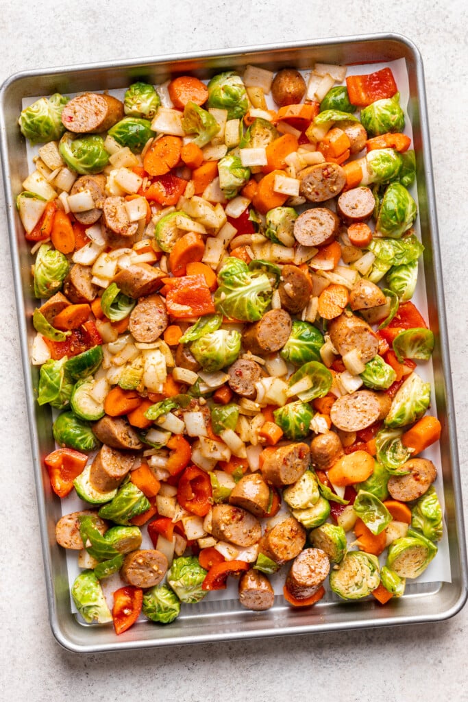 raw veggies and chicken sausage on a sheet pan