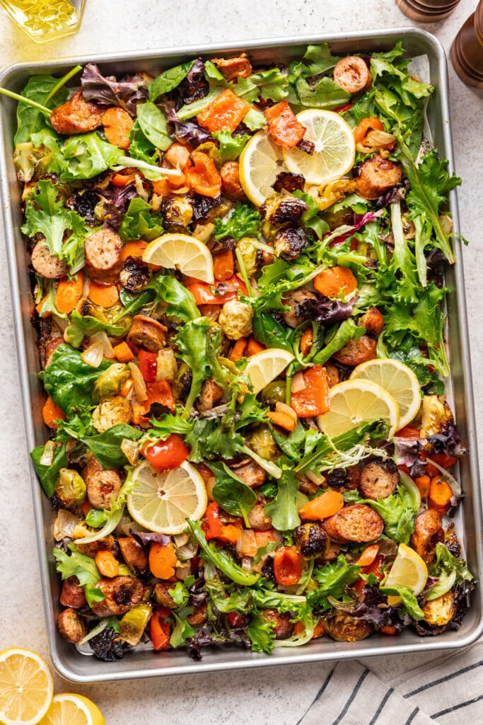 roast veggies and sausage on a sheet pan with greens and lemon