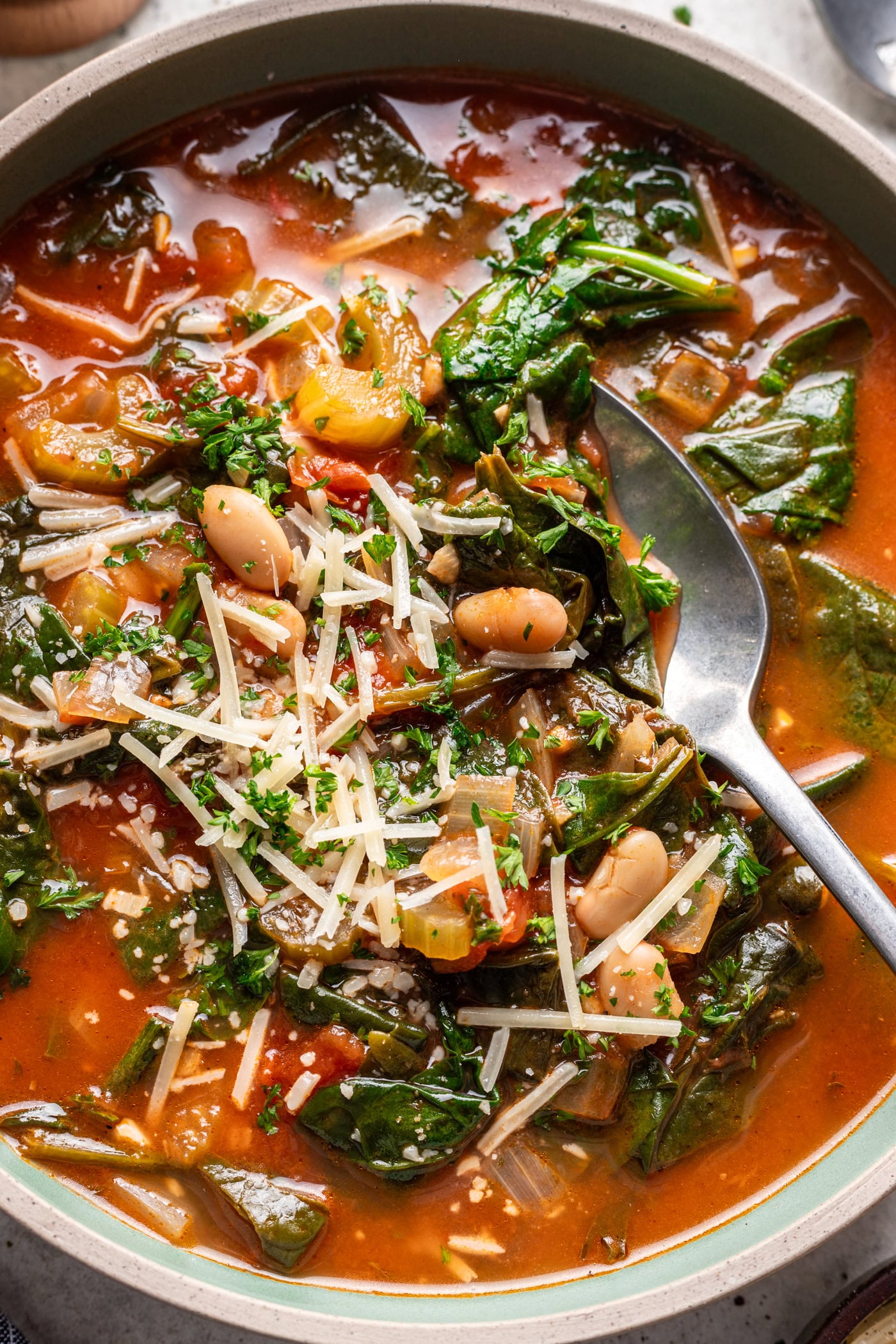 a bowl of spinach and white bean soup with a spoon