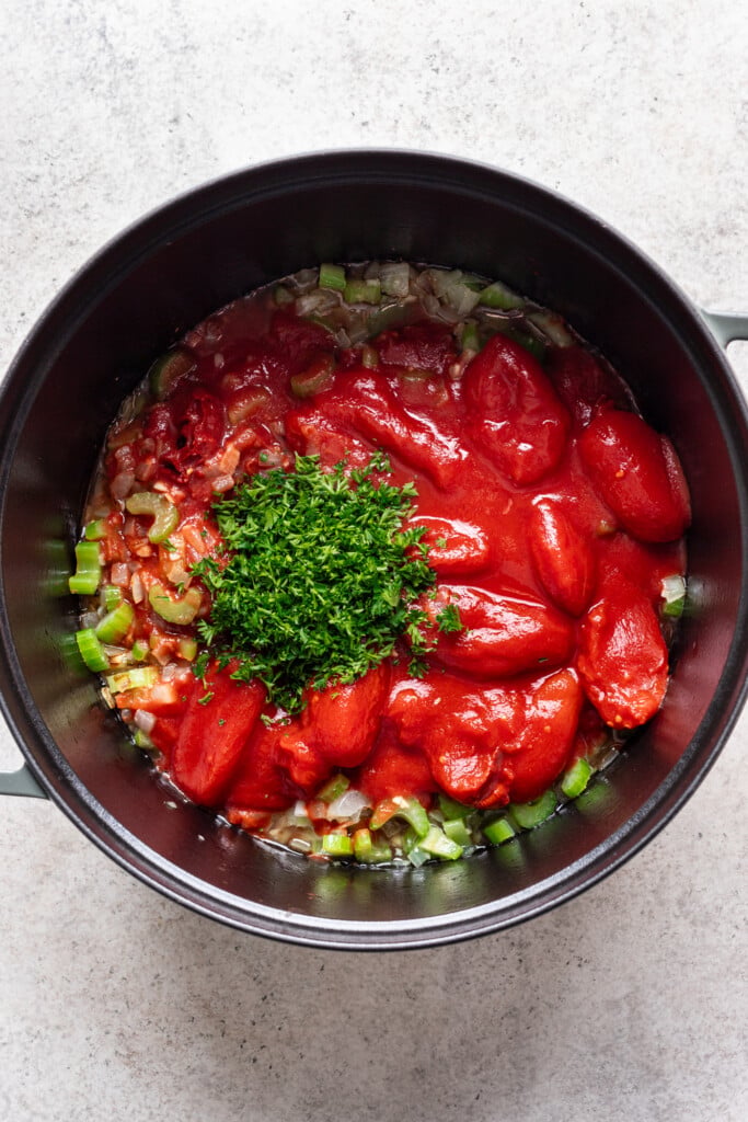 canned tomatoes with fresh herbs in a large soup pot