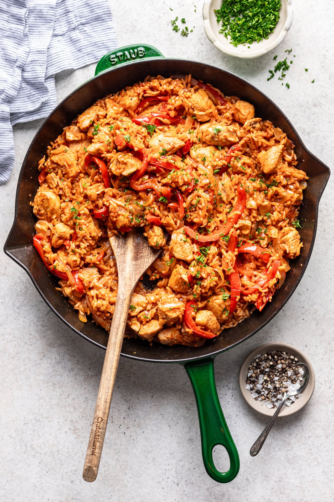 chicken and rice in a skillet with a wooden spoon