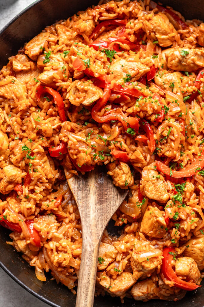 chicken and rice in a skillet with a wooden spoon