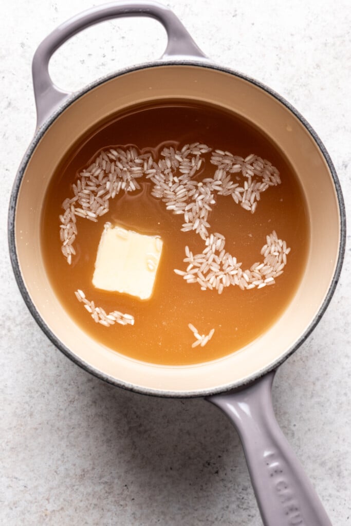 large pot with rice, broth and a pat of butter