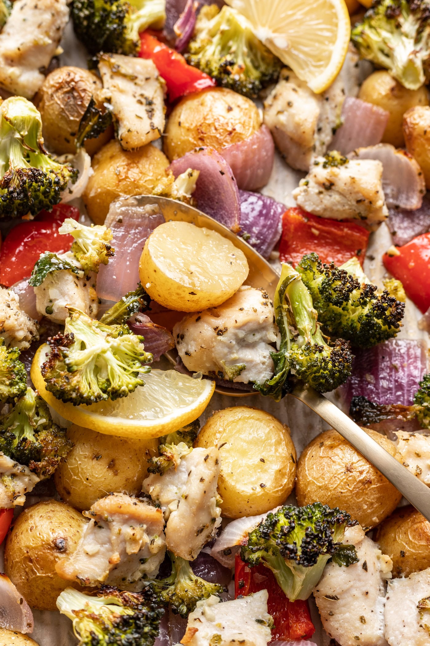 chicken and veggies sheet pan dinner with a spoon