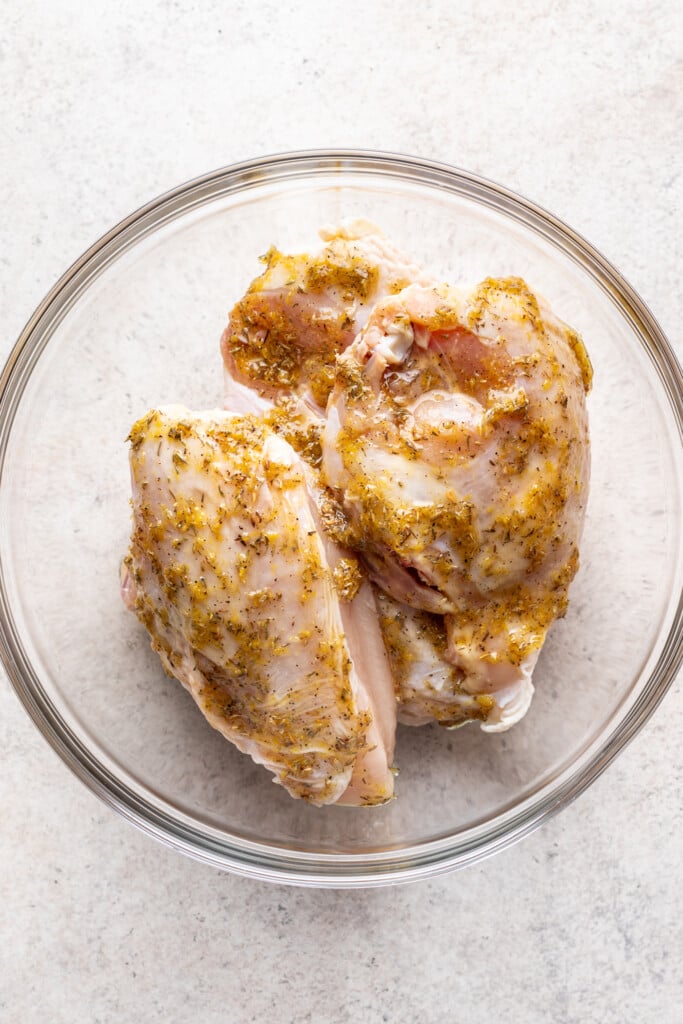 raw chicken pieces in a glass bowl with a marinade