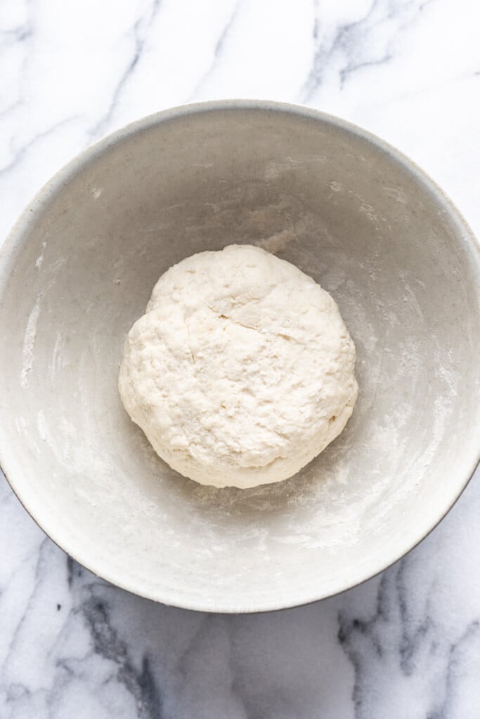 A bowl of dough on a marble counter