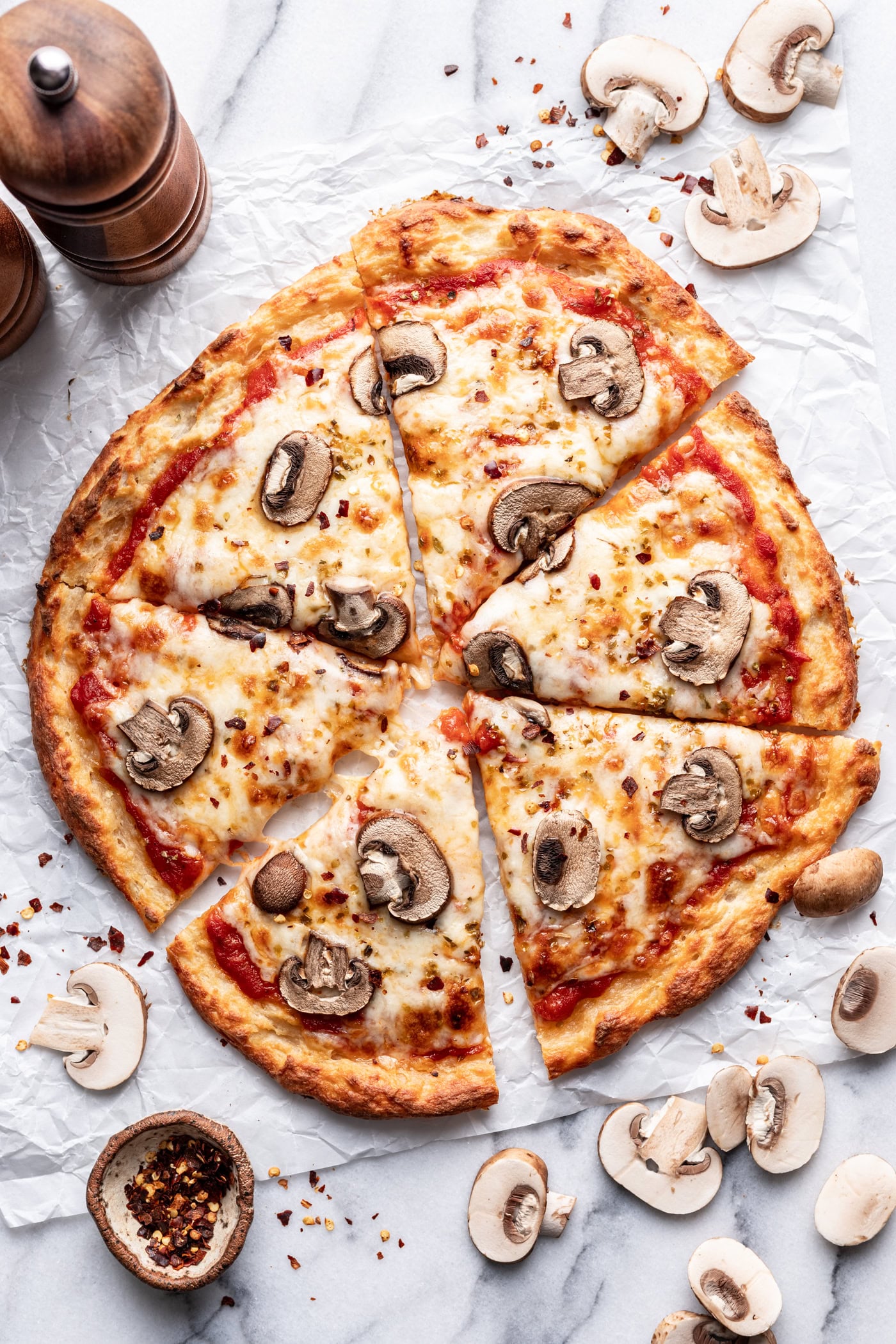 A pizza with mushrooms and cheese on a marble counter