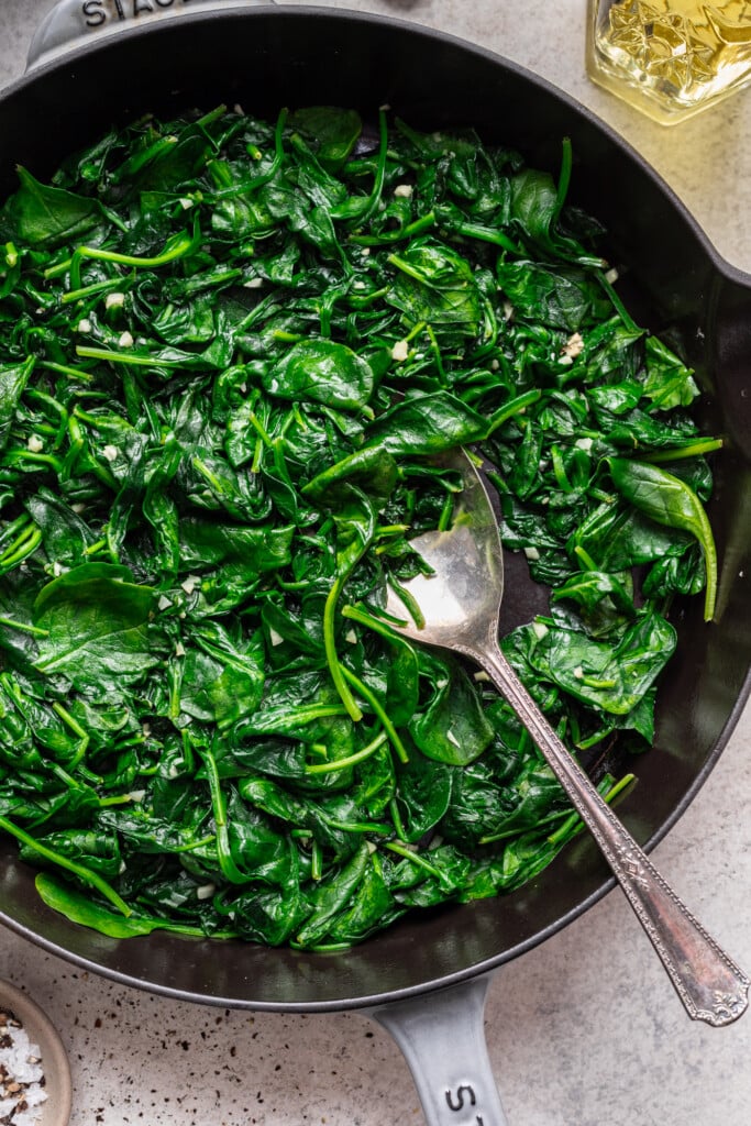sautéed spinach in a skillet with a serving spoon