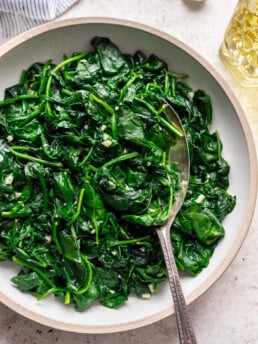 big bowl of sauteed spinach with a serving spoon