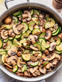 large skillet with sautéed mushrooms and zucchini