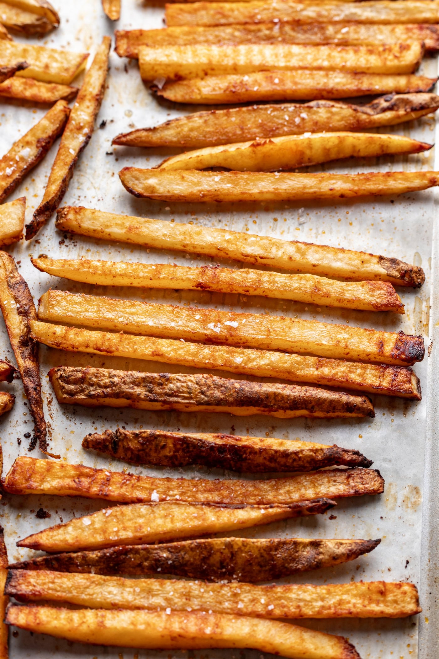 Crispy seasoned French fries on a parchment-lined baking sheet