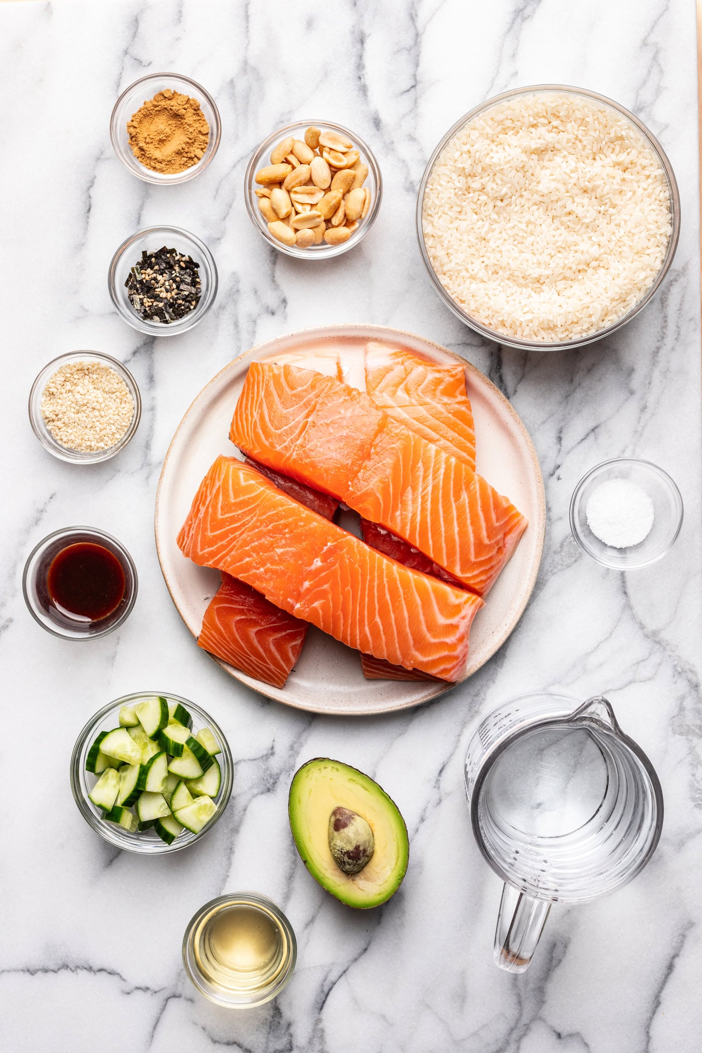 Fresh salmon fillets with rice, avocado, cucumbers, and various spices for healthy sushi bowls.
