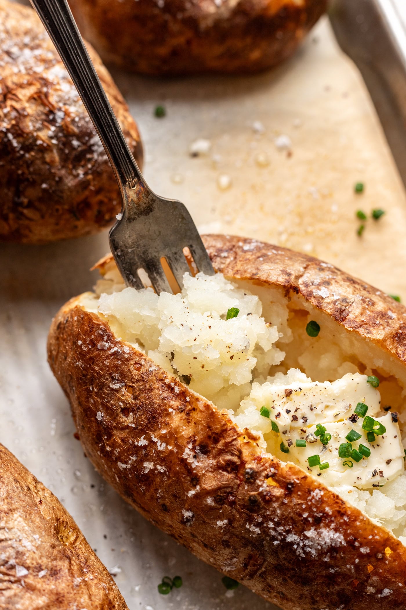 a fork fluffing the inside of a baked potato