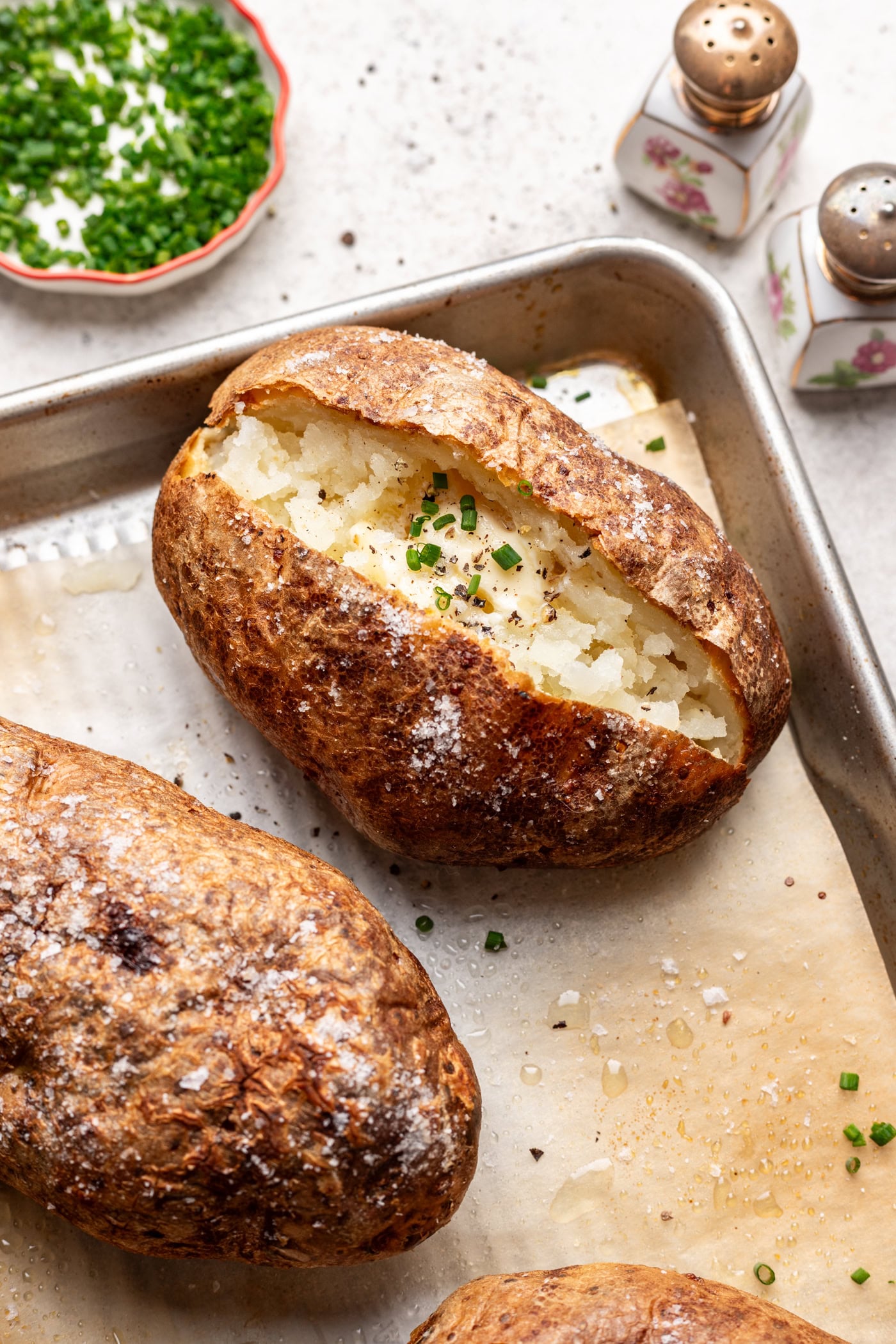 a baked potato open with butter and chives